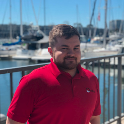 Jamie Edson, wearing a RedHat polo shirt. and standing on pier 